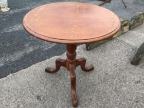 A Victorian mahogany tea table with circular moulded top tilting on a baluster turned column