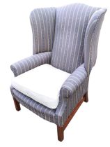 A Georgian style upholstered wing armchair, the arched back above a flared rectangular seat with
