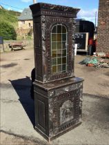 A Victorian oak carved cabinet with leaf carved cornice above an arched leaded glass door flanked by