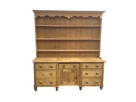 A Victorian pine dresser with later delft rack, the moulded cornice and shaped apron above three