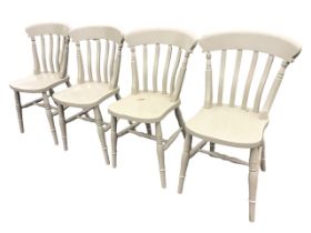 A set of four painted slatback chairs with solid dished seats raised on turned tapering legs