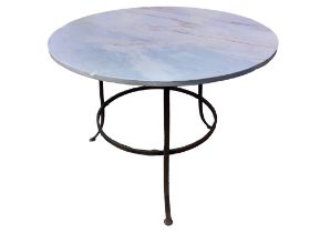 A circular marble topped garden table on three splayed wrought iron supports joined by ring