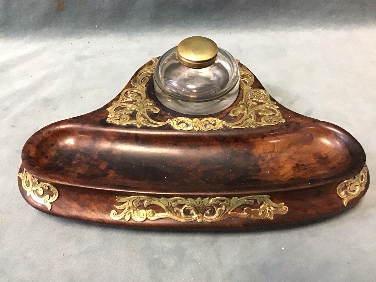 A Victorian walnut inkstand, with circular glass inkwell on a solid carved base with shaped pen