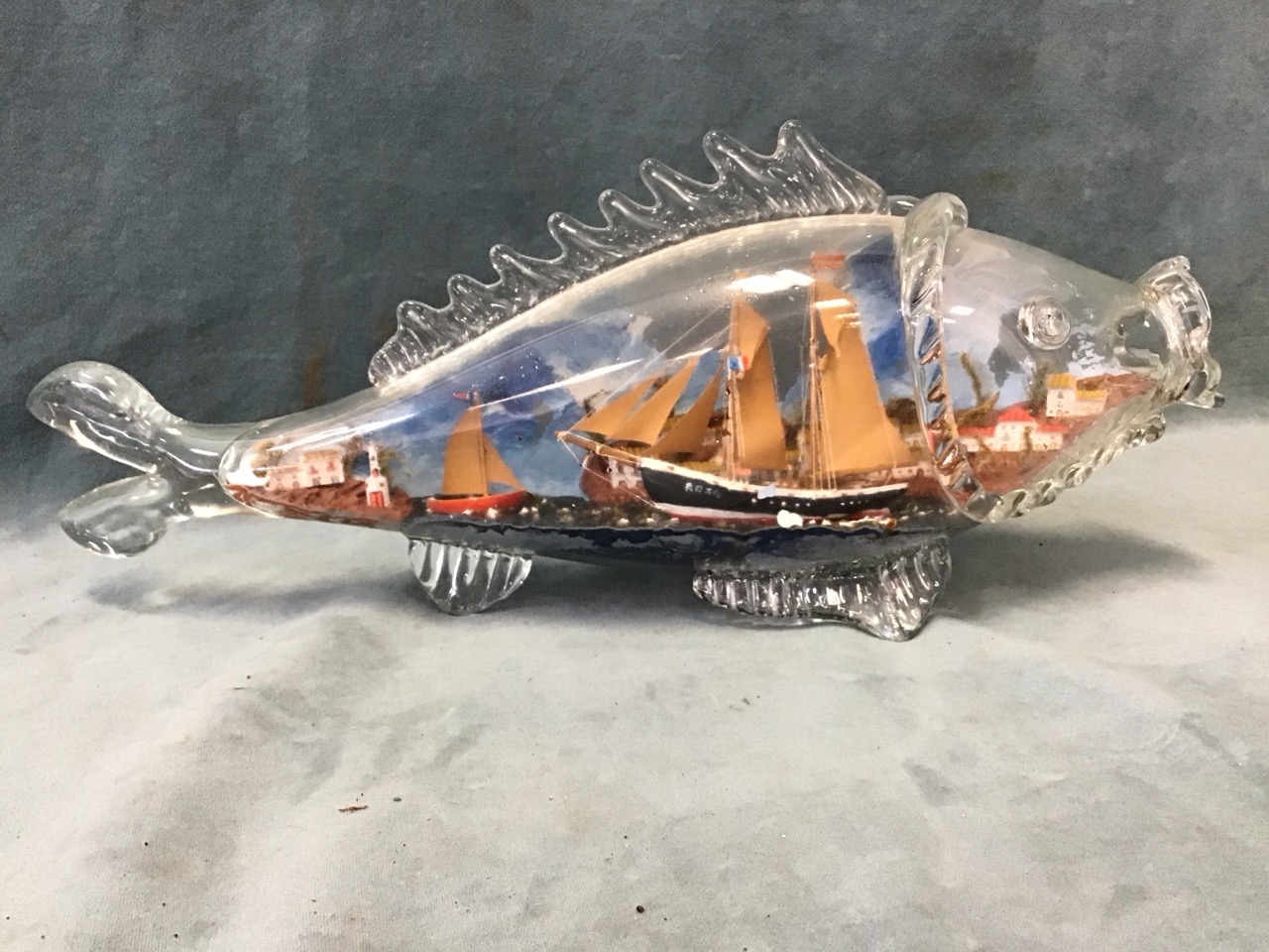 A ship in a bottle diorama with two sailing boats below a clifftop village in a square bottle - - Image 2 of 3