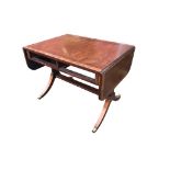 A crossbanded mahogany sofa table with rounded drop-ends raised on rectangular supports with sabre