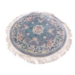 A circular Kayam Chinese wool rug with a central floral medallion on a pale blue ground within a