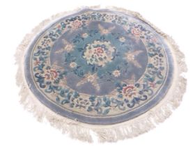 A circular Kayam Chinese wool rug with a central floral medallion on a pale blue ground within a