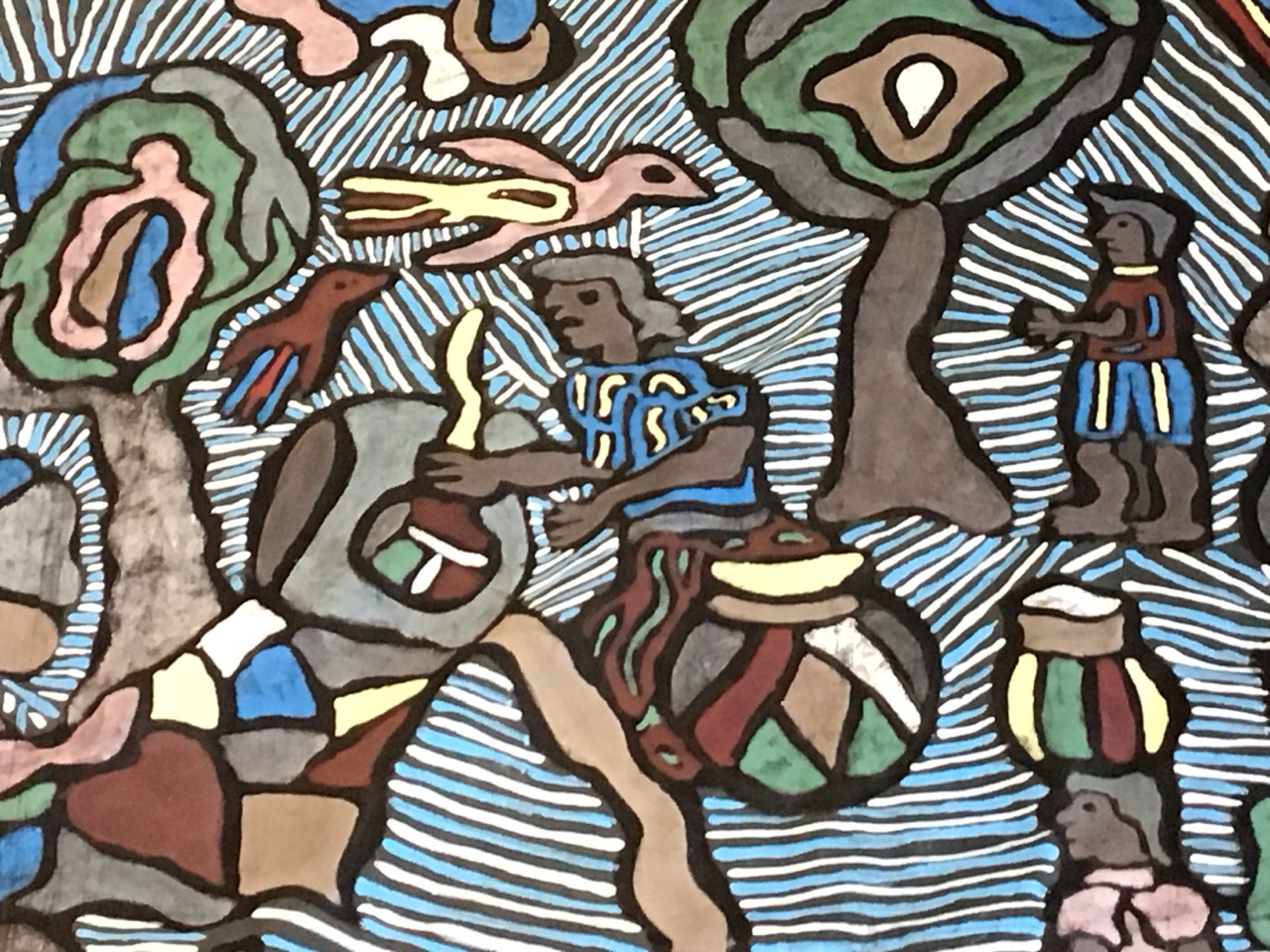 An African painted cotton wall hanging, depicting scenes of village life amongst trees and huts. ( - Image 2 of 3