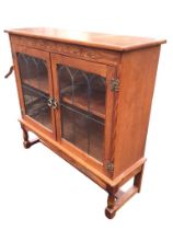 A rectangular oak cabinet with carved frieze above gothic leaded glass doors mounted with