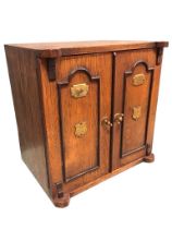 A Victorian oak cabinet modelled as a safe with ebonised panels to doors having brass mounts, the