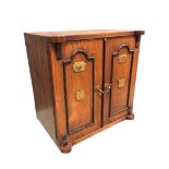 A Victorian oak cabinet modelled as a safe with ebonised panels to doors having brass mounts, the
