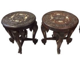 A pair of Indian carved hardwood occasional tables with circular tops inlaid with elephants,