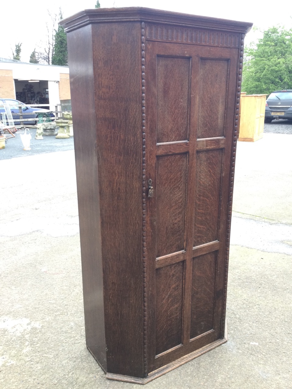 A 50s oak wardrobe with moulded cornice above a fluted frieze and six panelled door enclosing