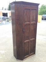 A 50s oak wardrobe with moulded cornice above a fluted frieze and six panelled door enclosing