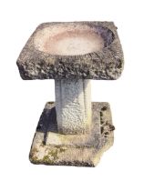 A composition stone garden birdbath with square bowl on tapering roughcast panelled column above a