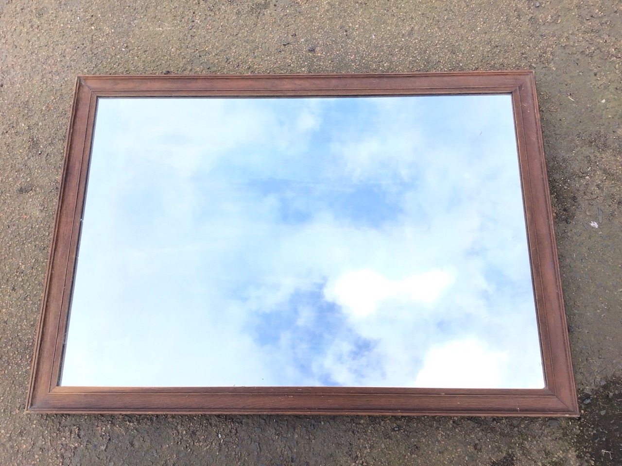 An Edwardian rectangular wall mirror in a moulded oak frame. (38in x 27.25in)