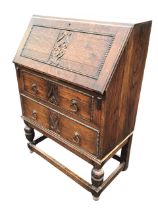 A 20s Jacobean style oak bureau, the bead moulded fallfront with scrolled panel enclosing a drawer &
