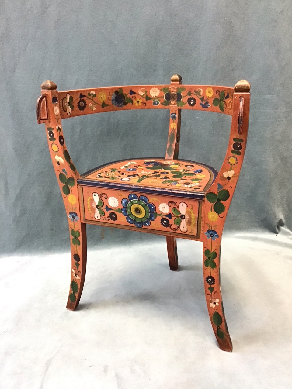 A Norwegian folk art childs chair with horseshoe shaped back and arms above a semicircular seat with