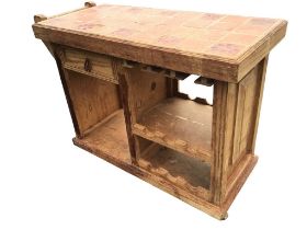 A rustic pine kitchen cart with rectangular tiled top and rail to the side above a moulded drawer,