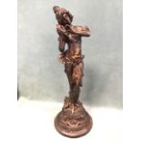 A cast iron figure with bronze patination depicting a classically draped lady listening a
