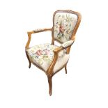 A carved hardwood fauteuil with floral brass studded needlework upholstery, the moulded back with