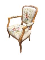 A carved hardwood fauteuil with floral brass studded needlework upholstery, the moulded back with