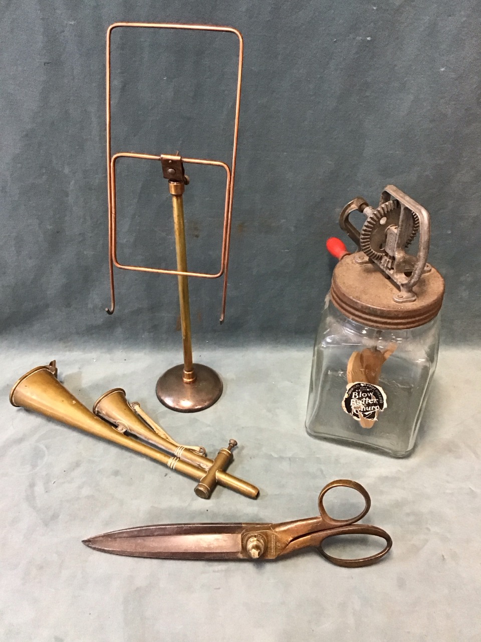 A 50s Blow glass butterchurn with wood paddles; an adjustable copper & brass shop display easel; a