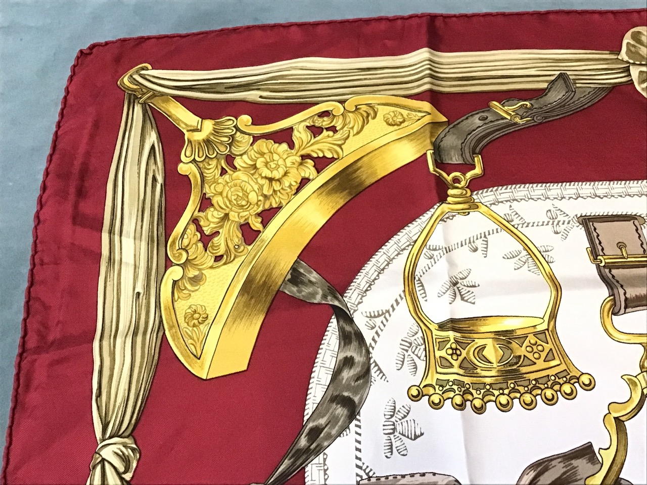 A silk Hermès scarf depicting a bell surrounded by various ornate stirrups, having deep red - Image 3 of 3