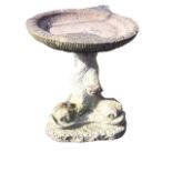 A composition stone garden birdbath with circular shallow ring moulded bowl on triangular dolphin