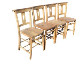 A set of four beech and elm church chairs with shaped flat backs and pierced splats above solid