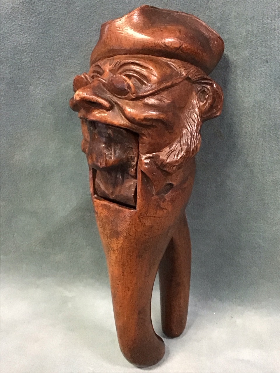 A C19th Swiss carved walnut nutcracker in the form of a comical old man wearing a tricorn hat and