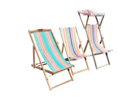 A folding hardwood deck chair with striped canvas seat and pierced handle; another similar with