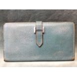 A pale blue Hermès leather wallet with four pouches and a zip compartment, having metal H clasp.