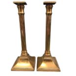A pair of Georgian brass candlesticks with square beaded sconces above reeded Tuscan columns on