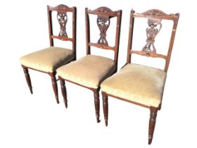 A set of three Edwardian mahogany chairs with carved arched backs and pierced vase foliate carved