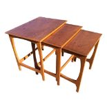 A 70s teak nest of three tables with rectangular tops raised on shaped legs joined by stretchers. (