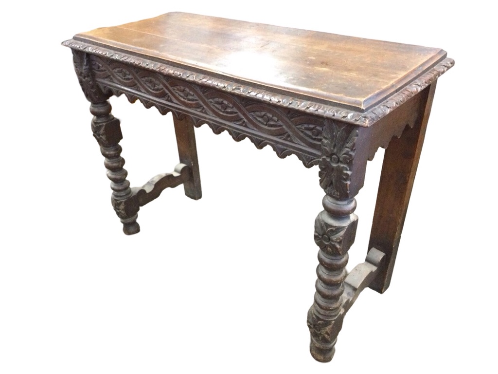 A Victorian oak jacobean style console table with rectangular leaf carved top above a waved ribbon