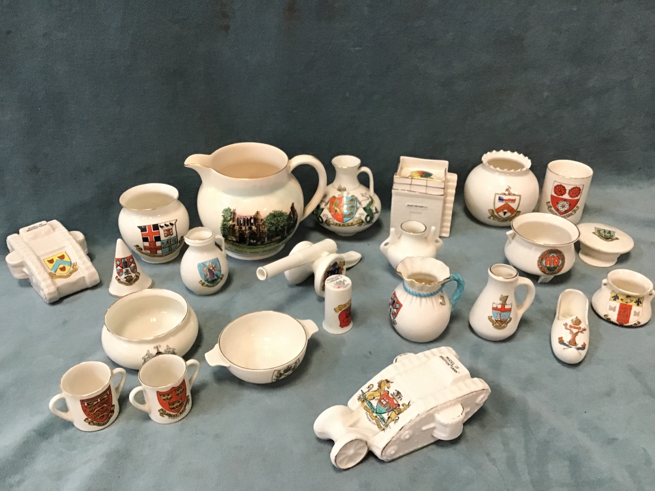 A collection of crested ceramics including two WWI tanks, a cannon, a military cap, a watchtower,