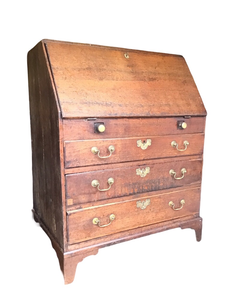 A Georgian oak bureau with rectangular sloping front opening on brass knobbed lopers enclosing