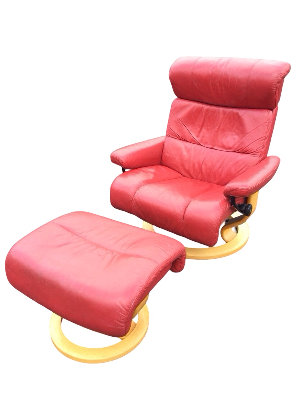 A stressless style leather armchair and footstool, with panelled upholstery and loose cushions,