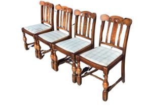 A set of four 30s oak dining chairs with slatted backs and shaped crestrails above drop-in