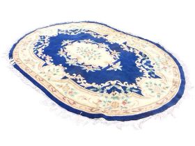 An oval Chinese aubusson style rug with central floral medallion on deep blue ground, within