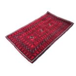 A Nahzat camel hair rug with three hooked medallions on a red ground within multiple flowerhead