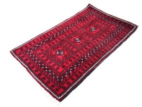 A Nahzat camel hair rug with three hooked medallions on a red ground within multiple flowerhead