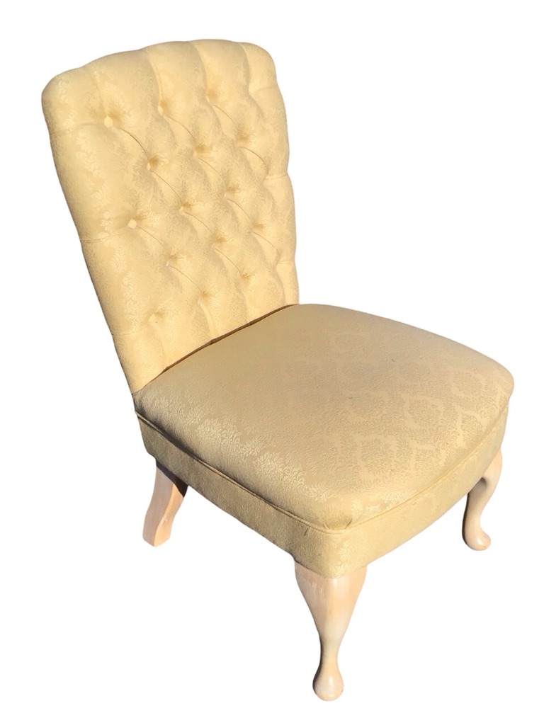 An upholstered chair with buttoned back and flared rectangular roundel seat raised on cabriole legs.