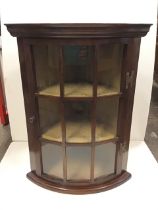 A C20th mahogany corner cabinet with moulded cornice above a glazed door enclosing three shelves,