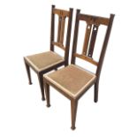 A pair of Edwardian art nouveau oak chairs with pierced crestrails and twin splats above upholstered