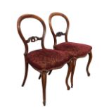 A pair of Victorian rosewood balloon back chairs with foliate carved pierced rails above upholstered