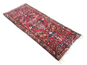 An Azerbaijani wool rug with flower vase motifs on a red ground, within geometric foliate