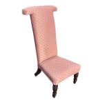 A Victorian prie-dieu chair, the high upholstered back above a flared seat, raised on turned
